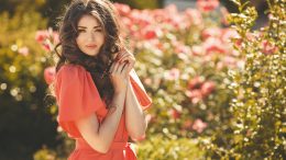 Beautiful woman in a summer garden blossoming roses.